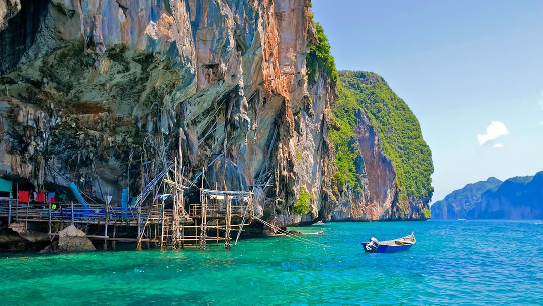 Viking Cave with wooden scaffolding and boat in turquoise waters, Ko Phi Phi, Thailand.