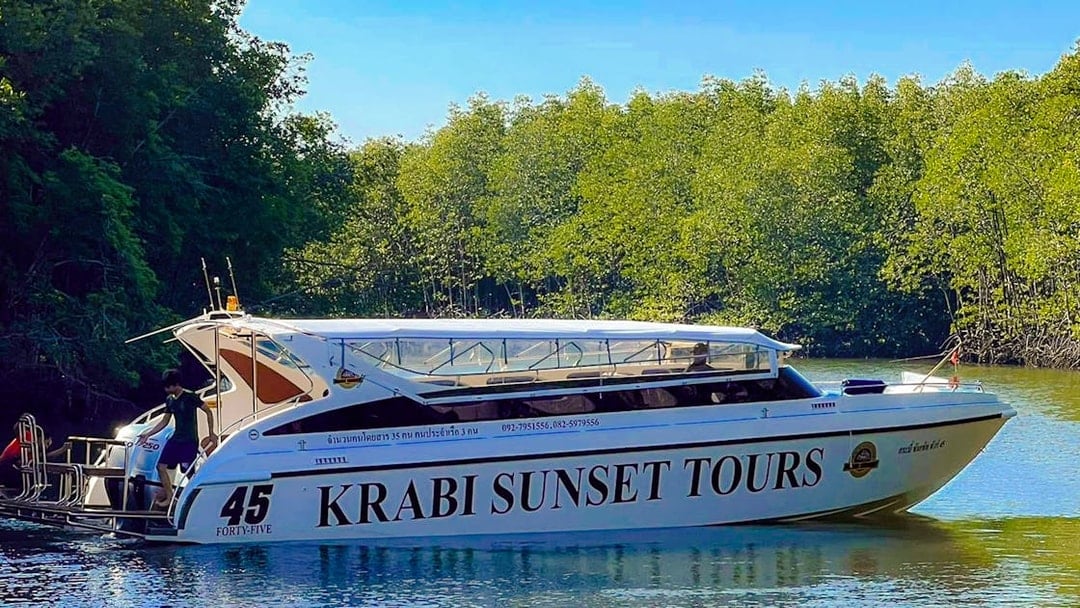 Speedboat for Krabi Sunset Tours on water near lush greenery, Phi Phi Islands.