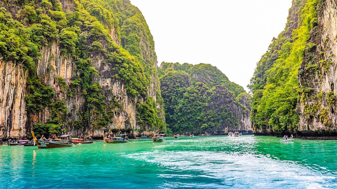 Longtail boats in turquoise waters of Pileh Lagoon, surrounded by limestone cliffs, Krabi.