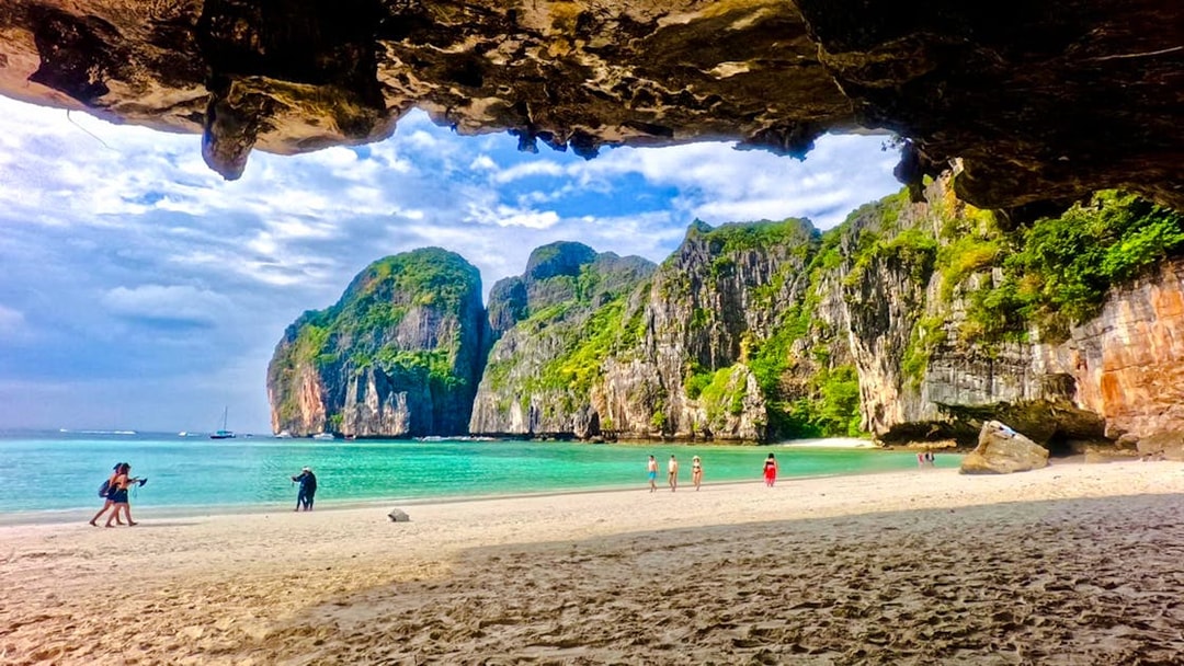 Beach view with tourists at Maya Bay, Phi Phi Islands, Krabi, surrounded by limestone cliffs.