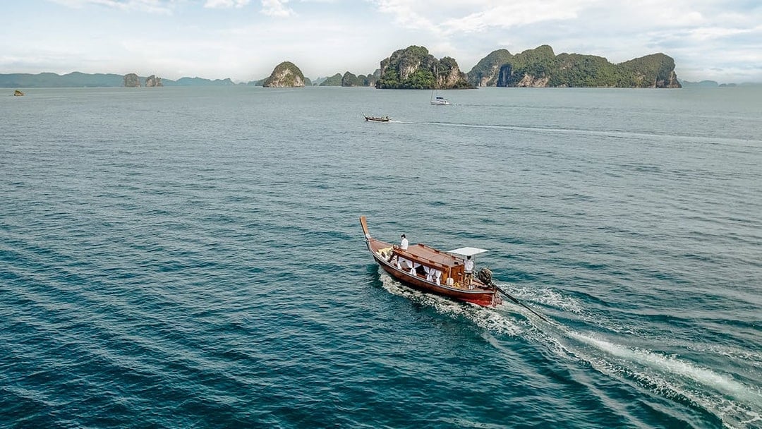 Longtail boat sailing near limestone islands in Krabi, Thailand.