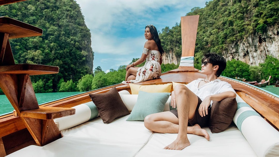 Longtail boat sailing in Krabi with limestone cliffs and lush greenery in the background.