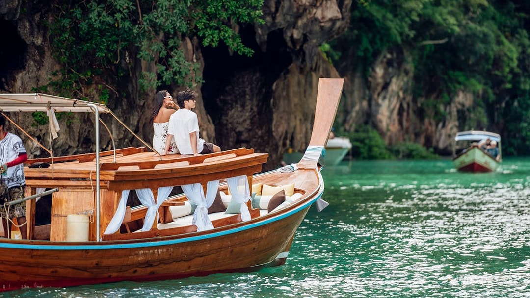 Longtail boat sailing near limestone cliffs in Krabi, Thailand.