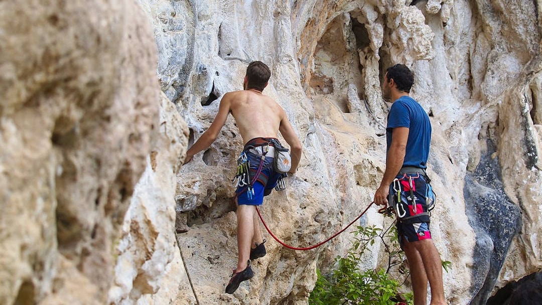 Rock climbers scaling limestone cliffs at Railay Beach, Krabi during a climbing course.