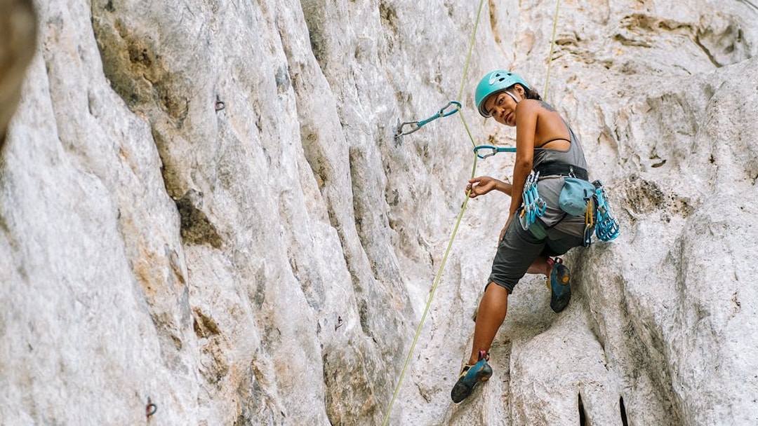 Female climber scaling limestone cliff in Krabi, Thailand.