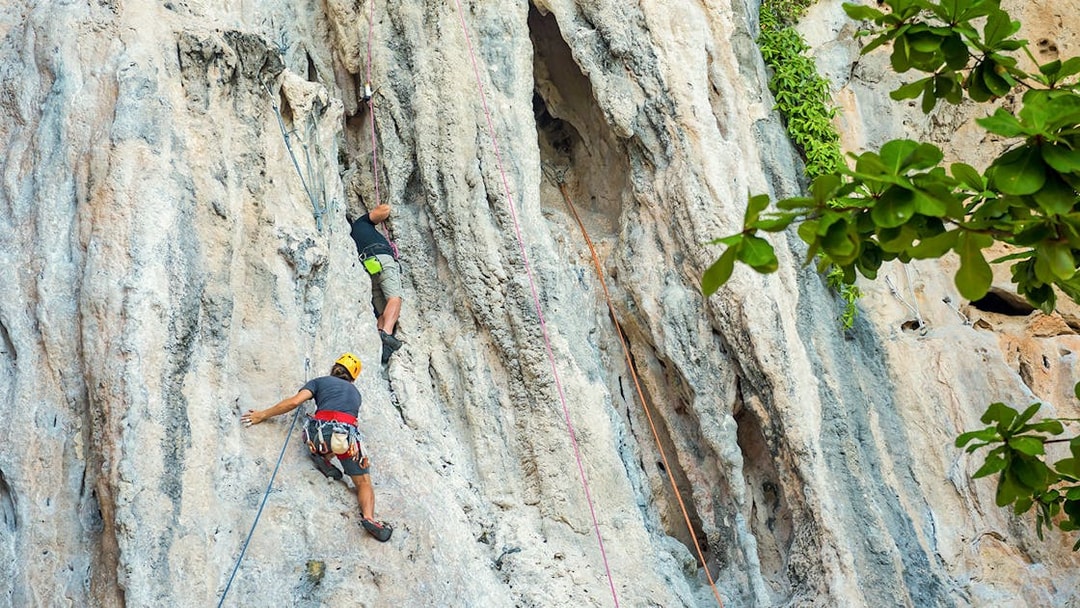 Rock climbers scaling limestone cliffs at Railay Beach, Krabi during a climbing course.