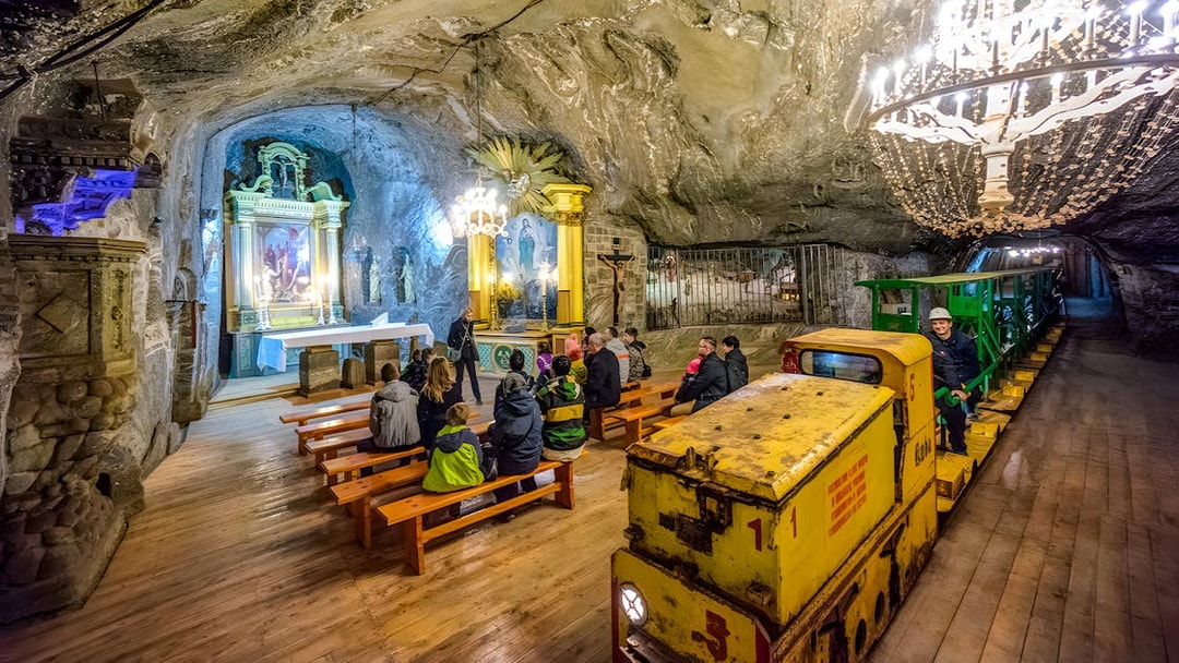 Visitors seated in Bochnia Salt Mine chapel with underground train in view.