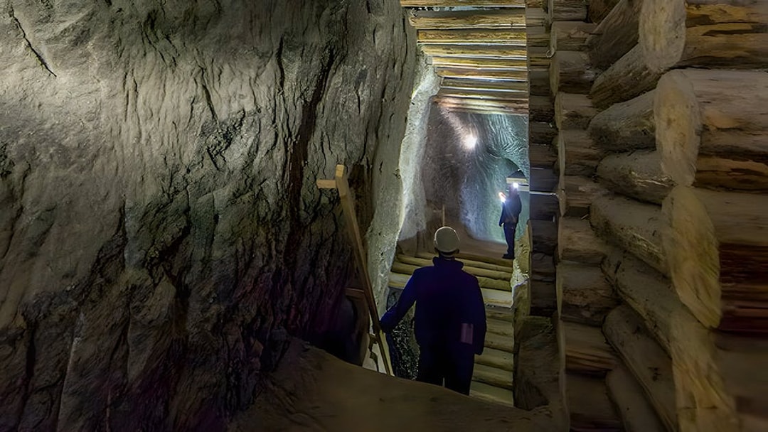 Visitors exploring Bochnia Salt Mine tunnel with wooden supports.