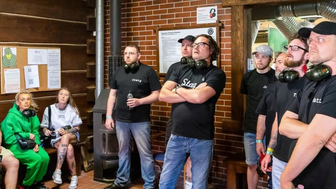 Group of people listening to instructions at an indoor shooting range.