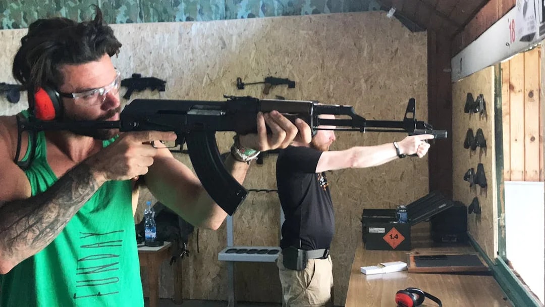 Participants aiming rifles at an indoor shooting range.