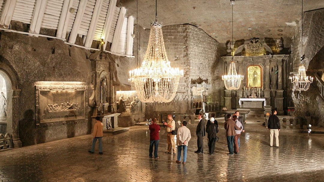 Visitors exploring the Wieliczka Salt Mine chapel with chandeliers and salt carvings.