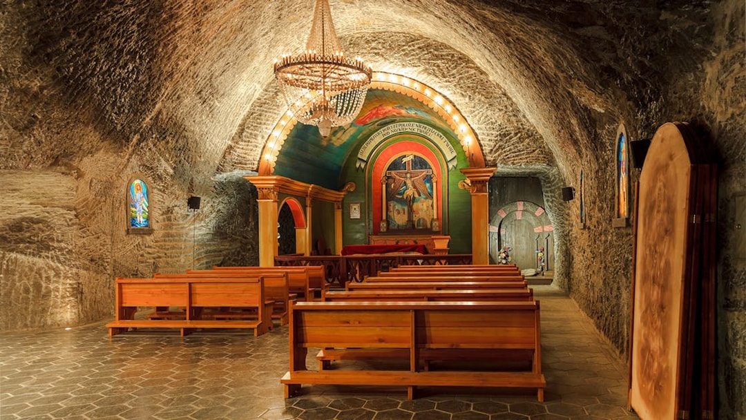 St John Chapel interior in Wieliczka Salt Mine with wooden benches and ornate altar.