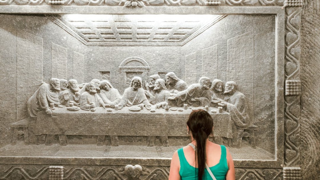 Visitor admiring salt carving of The Last Supper at Wieliczka Salt Mine.