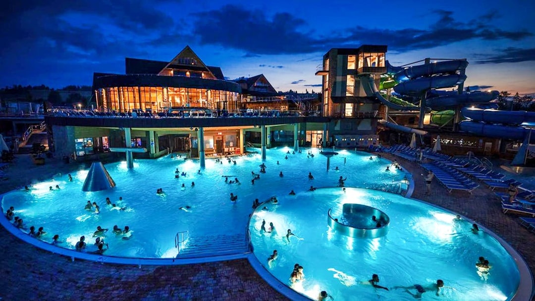 Zakopane Thermal Baths at night with illuminated pools and water slides.