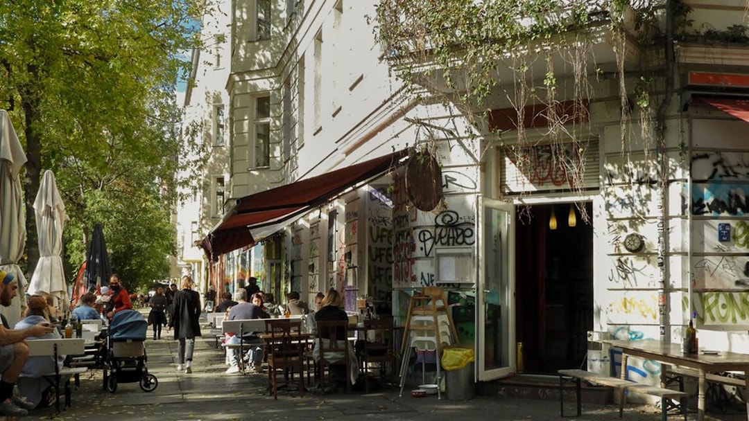 Outdoor cafe scene in Kreuzberg with people dining along a graffiti-covered street.