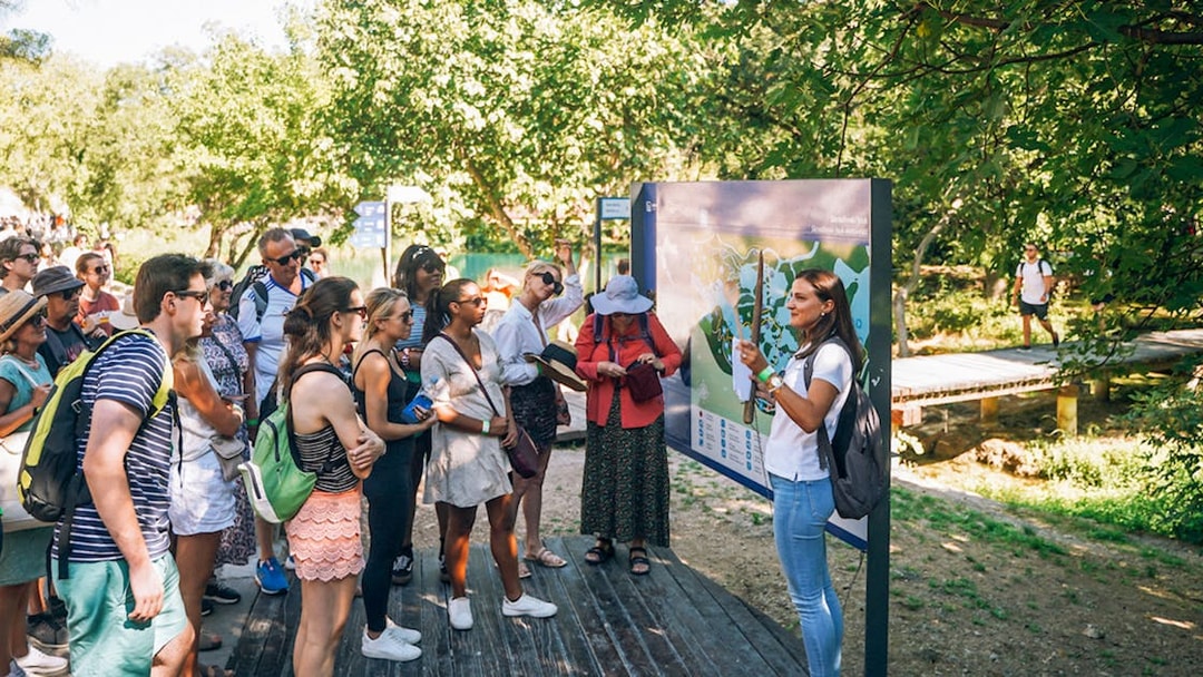 Tour group listening to a guide at Krka National Park, Croatia, near a map display.