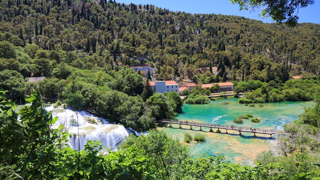 Bridge over turquoise water leading to Krka waterfall at Krka National Park, Croatia.