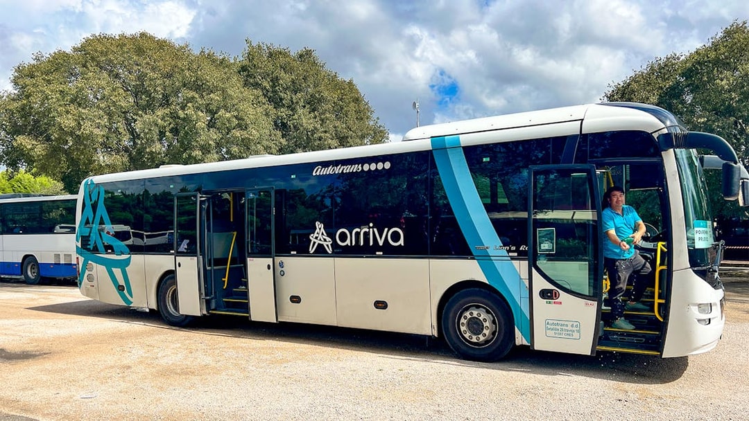 Bus for transfers to Krka National Park with driver at the door.