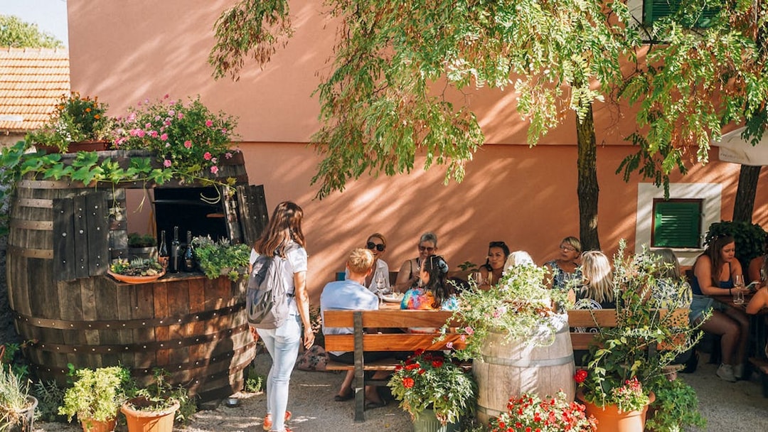 Group enjoying wine tasting at Krka National Park, Croatia, seated outdoors near a rustic barrel.