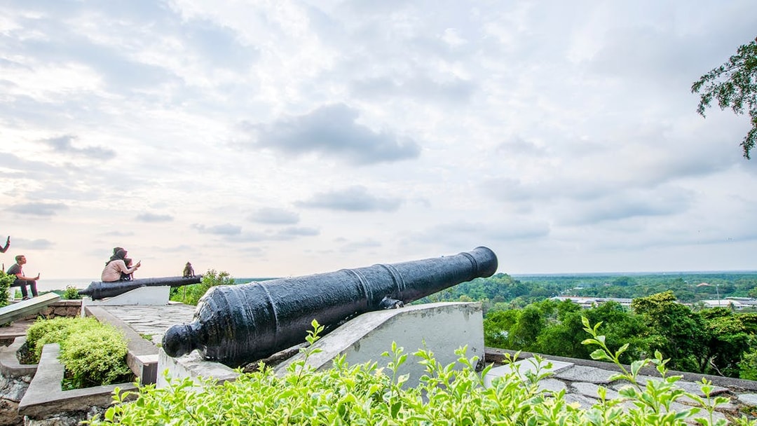 Historic cannon overlooking lush landscape on Kuala Lumpur and Batu Caves tour.