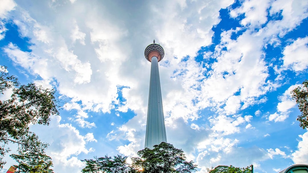 Kuala Lumpur Tower against a blue sky during a guided tour.