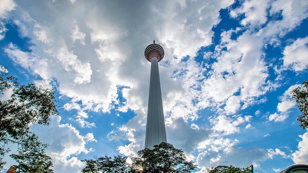 Kuala Lumpur Tower against a cloudy sky on the Putrajaya & Batu Caves Private Tour.