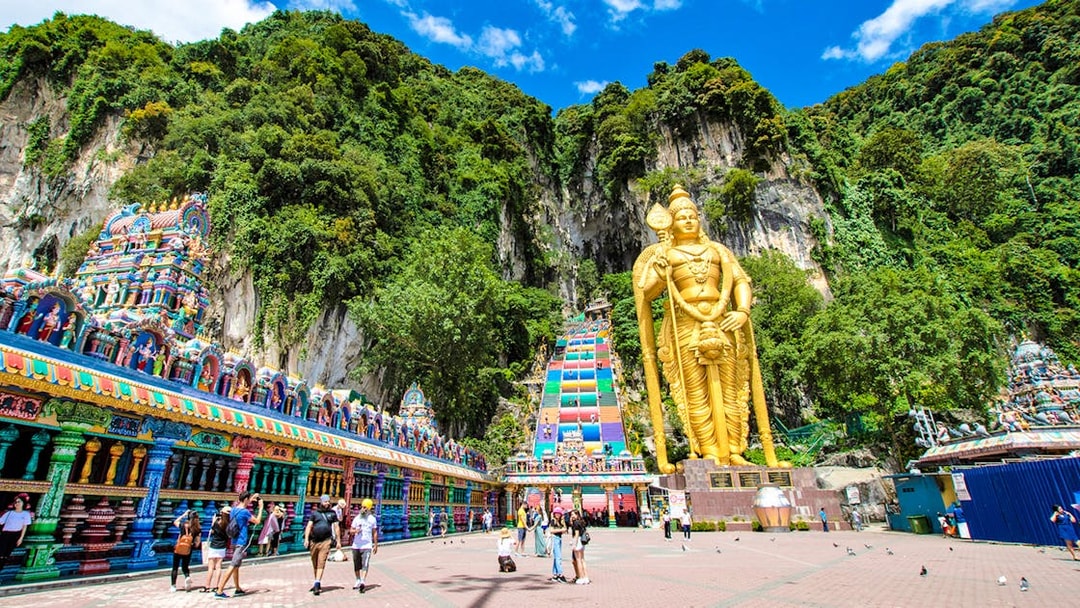 Batu Caves entrance with golden statue and colorful temple facade, Malaysia.