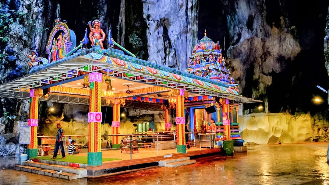 Colorful temple inside Batu Caves, Malaysia, with intricate carvings and visitors exploring.