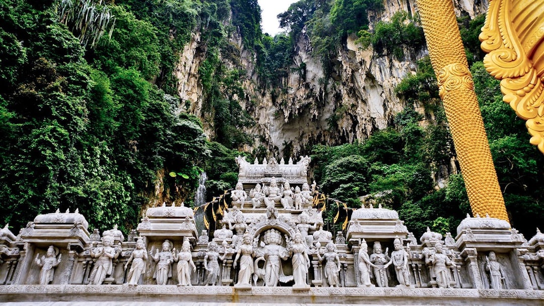 Batu Caves temple facade with intricate statues and lush limestone cliffs in Kuala Lumpur.