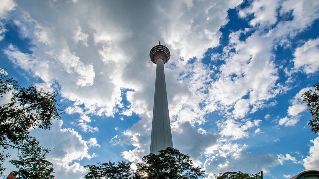 Kuala Lumpur Tower against a cloudy sky during the Half Day City Tour.