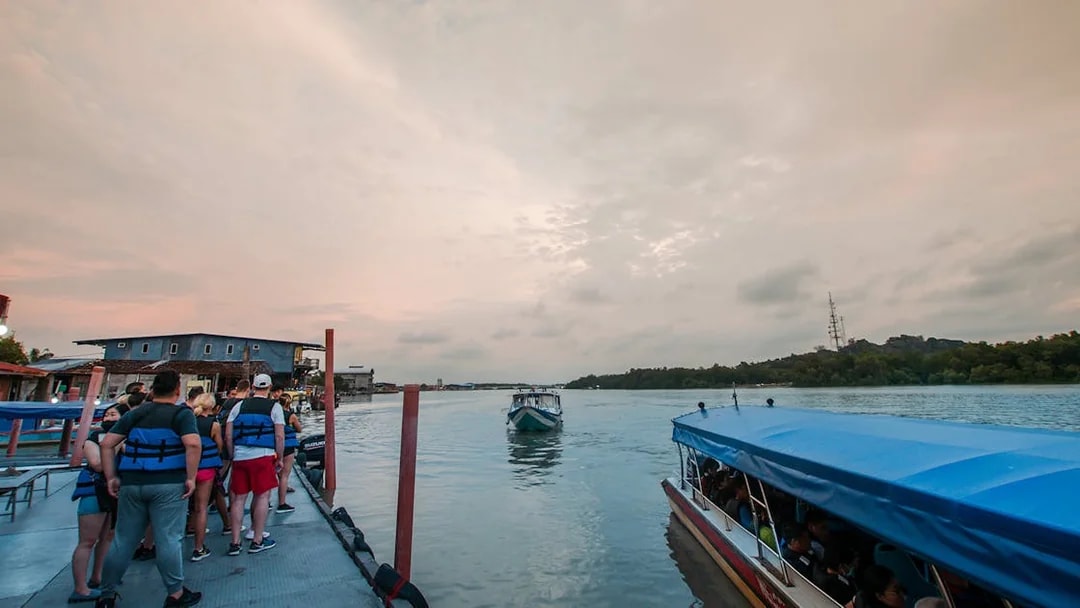 Tourists boarding a boat at sunset for the Kuala Selangor Fireflies Night Tour.