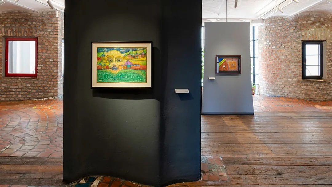 KUNST HAUS WIEN exhibit featuring colorful Hundertwasser paintings on brick walls.