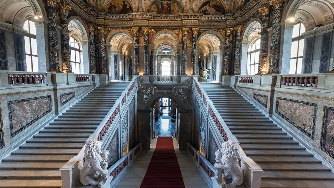 Staircase inside Kunsthistorisches Museum, Vienna, with ornate marble and sculptures.