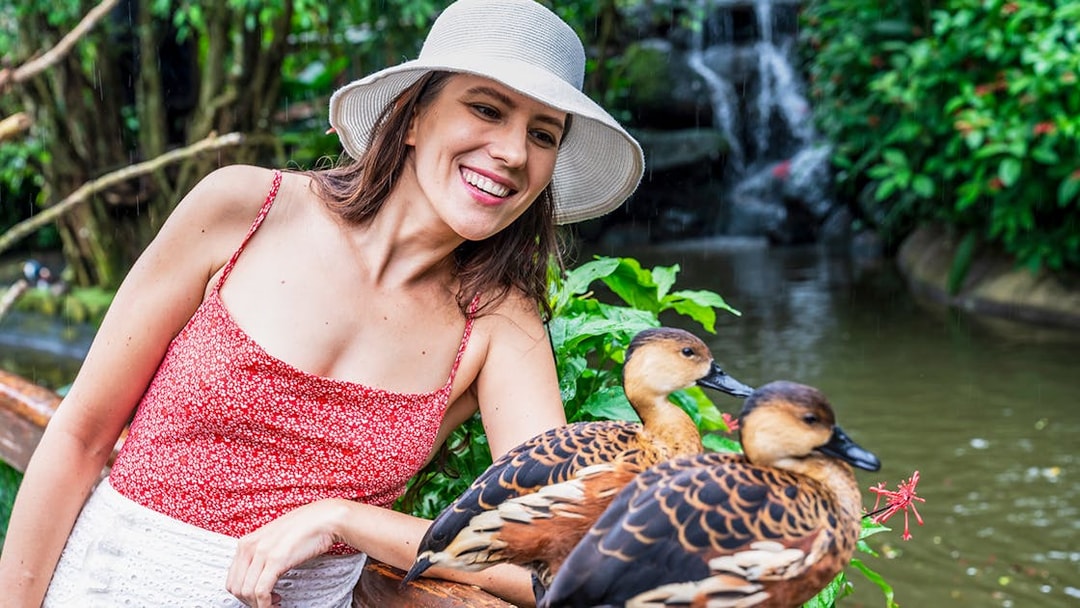 Woman smiling at ducks by a pond at Birdworld Kuranda.