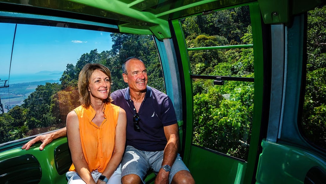 Couple enjoying Kuranda Skyrail Cableway with rainforest and coastline views in Cairns, Australia.