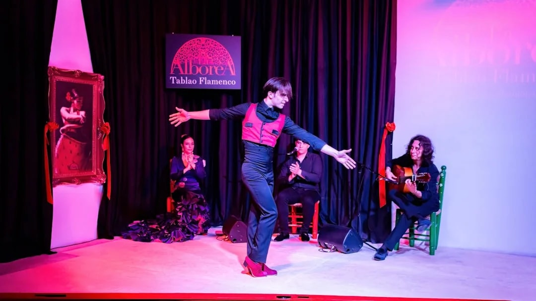 Flamenco dancer performing at La Alboreá in Granada with musicians on stage.