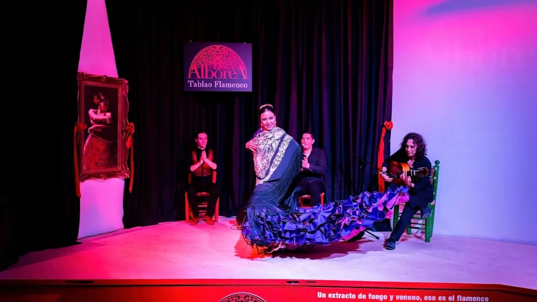 Flamenco dancer performing at La Alboreá Tablao Flamenco with musicians on stage.