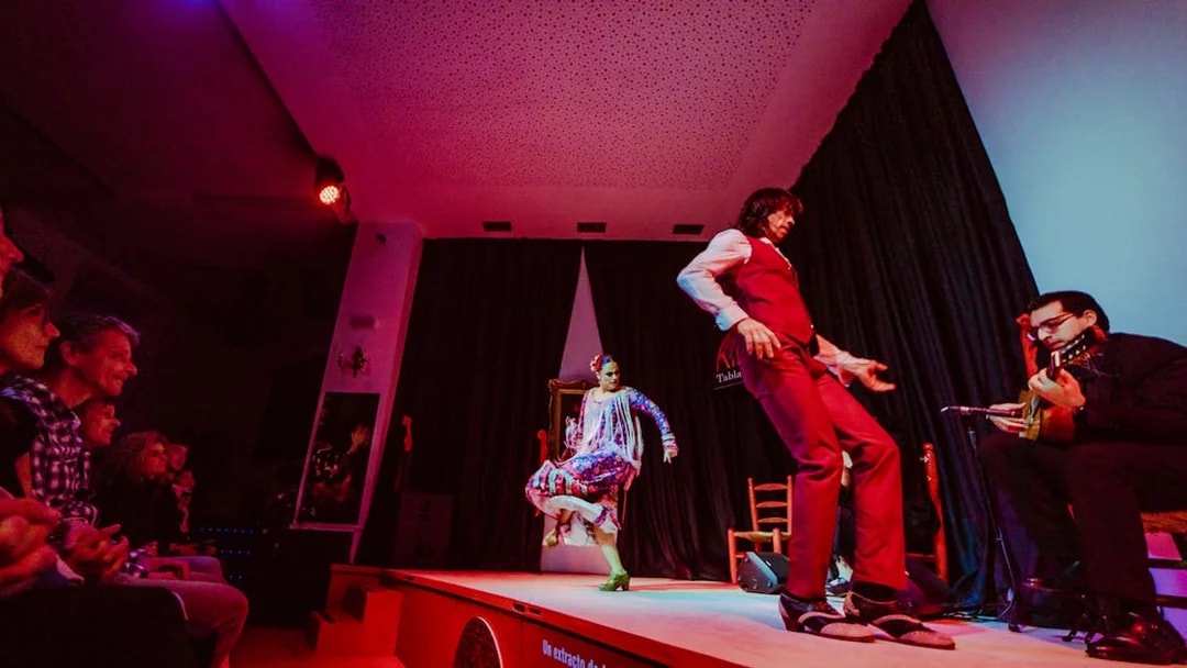 Flamenco dancers performing on stage at La Alboreá, Granada, with a guitarist playing.