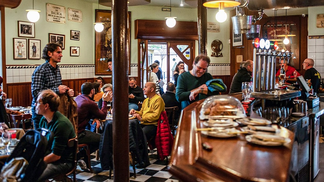 People enjoying a meal in a bustling La Barceloneta restaurant during a guided food tour.