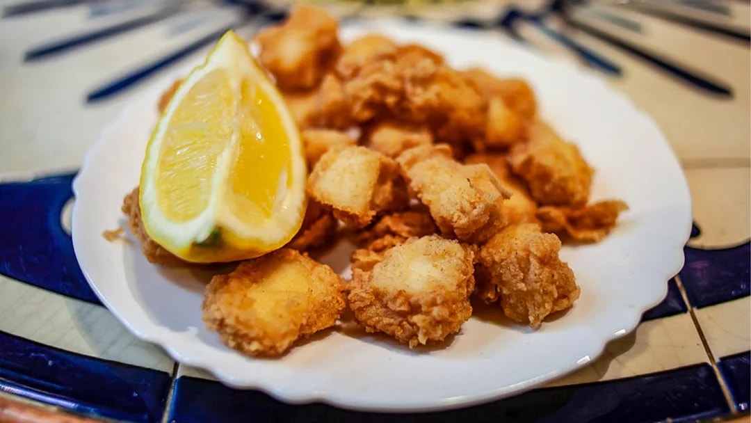 Fried seafood with lemon on a plate during La Barceloneta food tour.