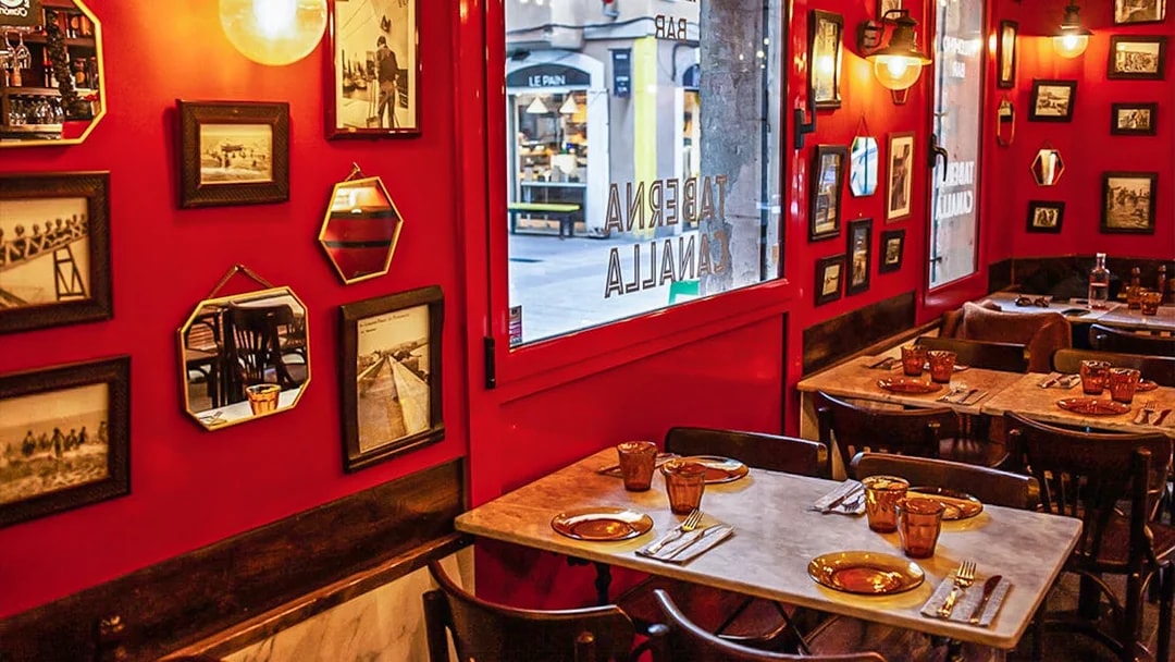 Cozy restaurant interior in La Barceloneta with red walls and framed photos, part of a 3-hour guided food tour.