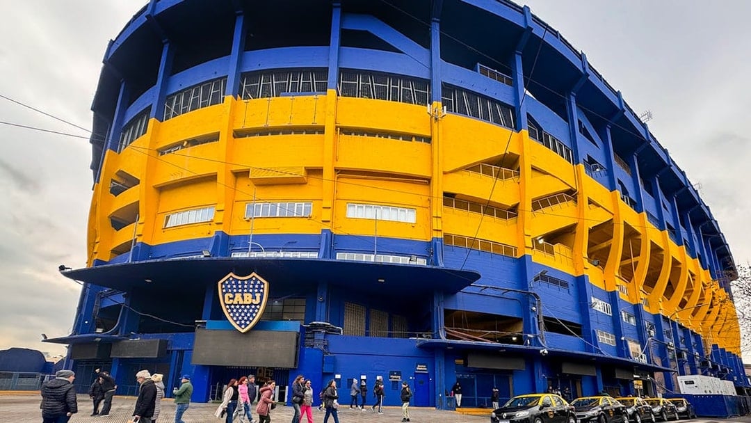 La Bombonera stadium exterior with people walking and taxis parked, Buenos Aires.