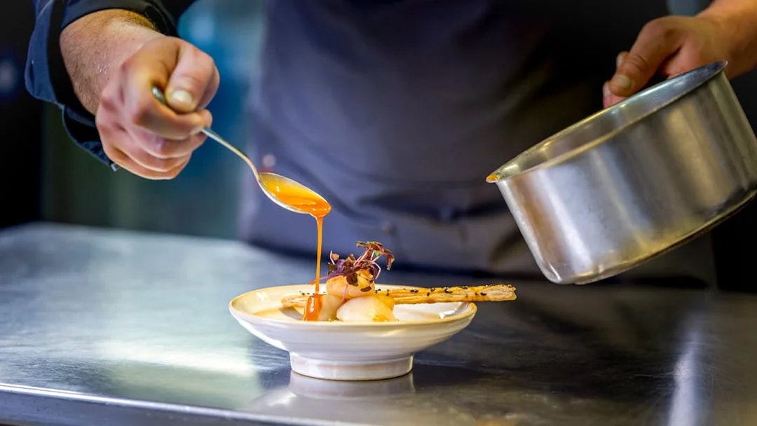 Chef preparing gourmet dish on La Marina dinner cruise.