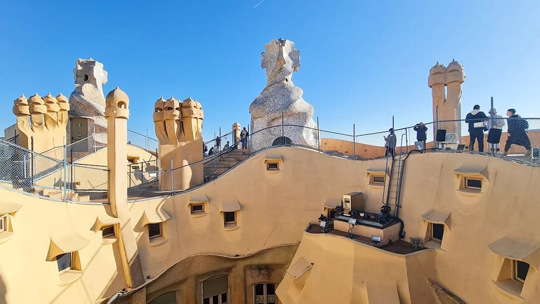 La Pedrera Casa Mila rooftop with unique chimneys and visitors in Barcelona.