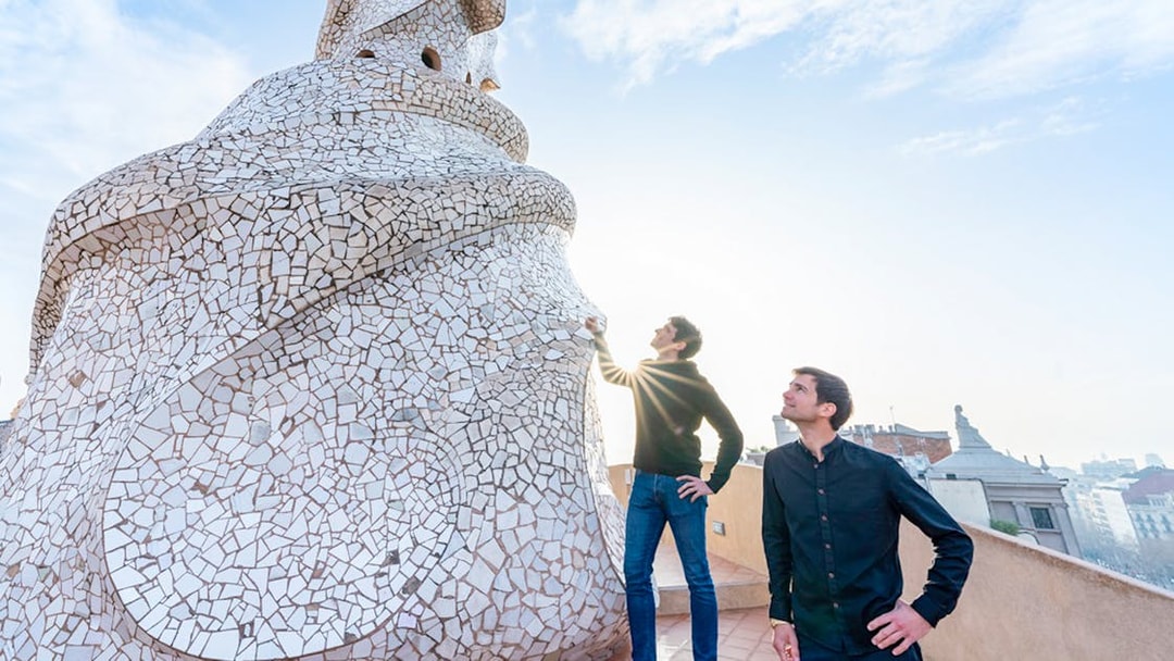 Visitors exploring the mosaic chimneys on Casa Mila rooftop in Barcelona.