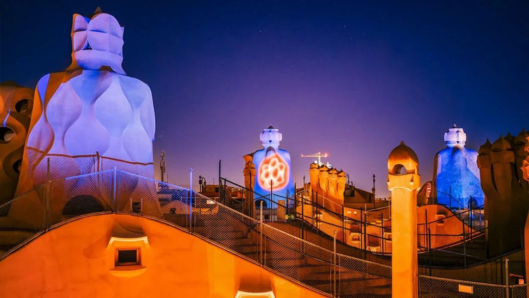 Casa Mila rooftop chimneys illuminated during La Pedrera Night Experience in Barcelona.