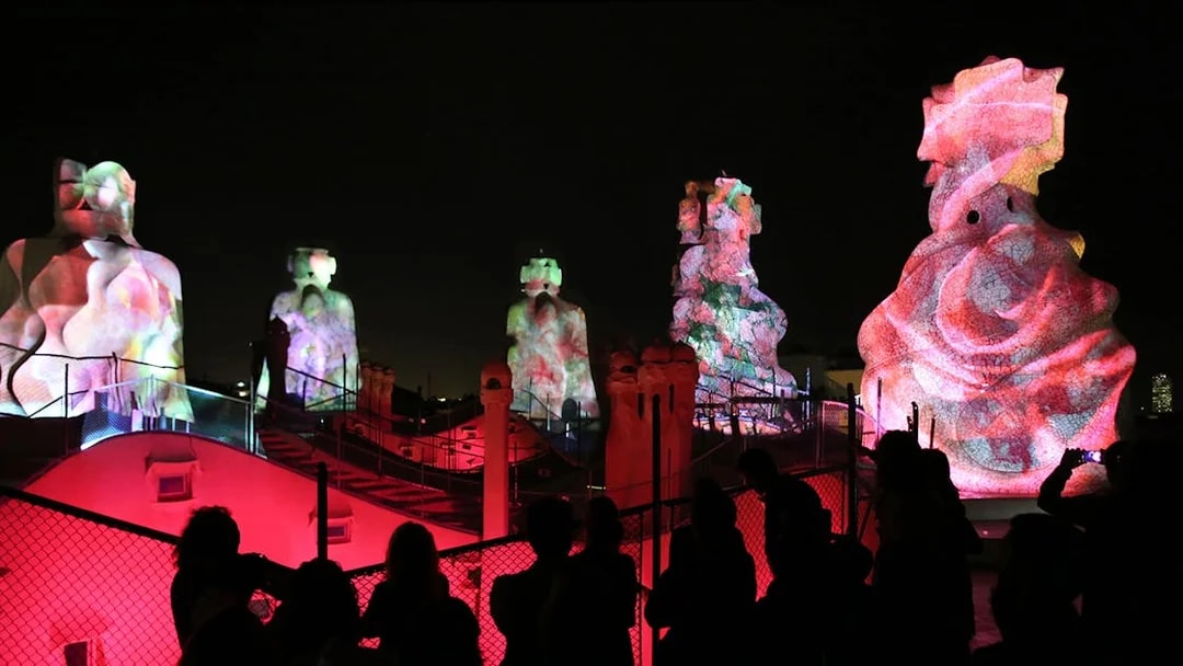 Casa Mila rooftop sculptures illuminated during La Pedrera Night Experience in Barcelona.