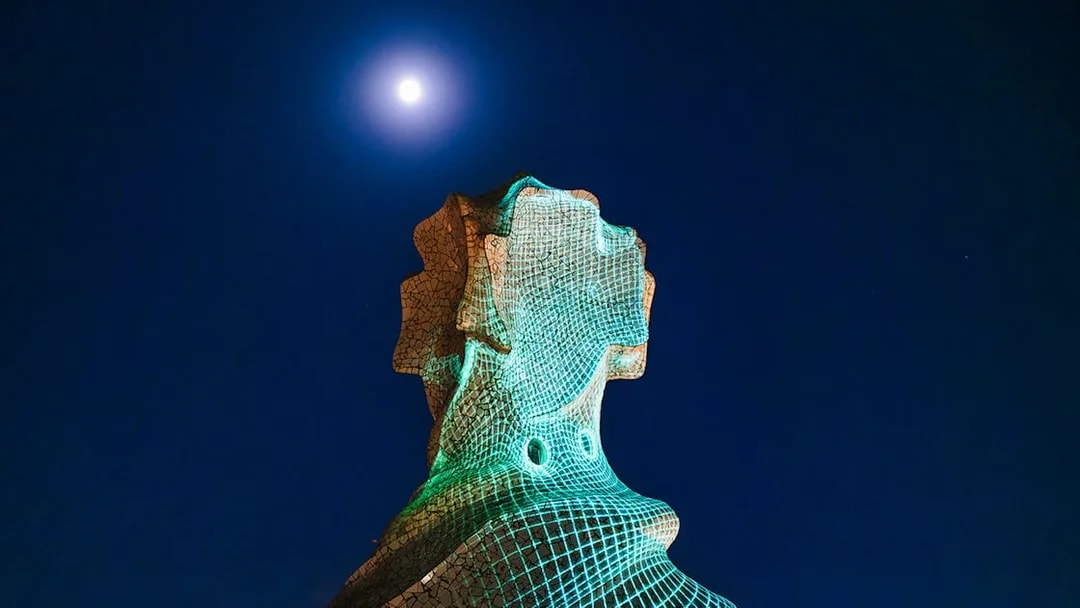 Chimney sculpture at Casa Mila-La Pedrera illuminated at night under a full moon.