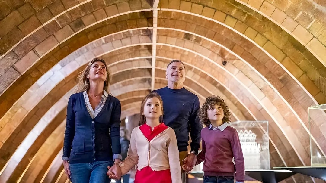 Family exploring Gaudí's La Pedrera attic arches on a guided tour in Barcelona.