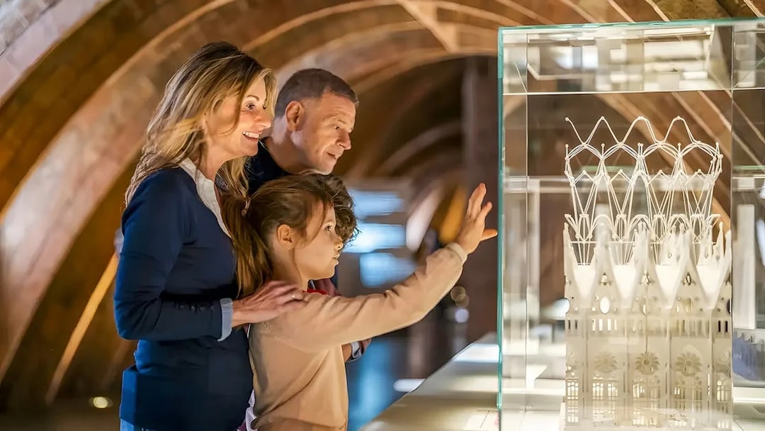 Family observing Casa Mila miniature in Barcelona exhibit.